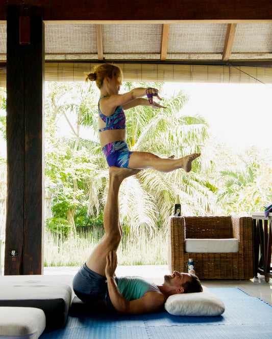 AcroYoga base supporting a flyer during outdoor L-basing practice in Bali