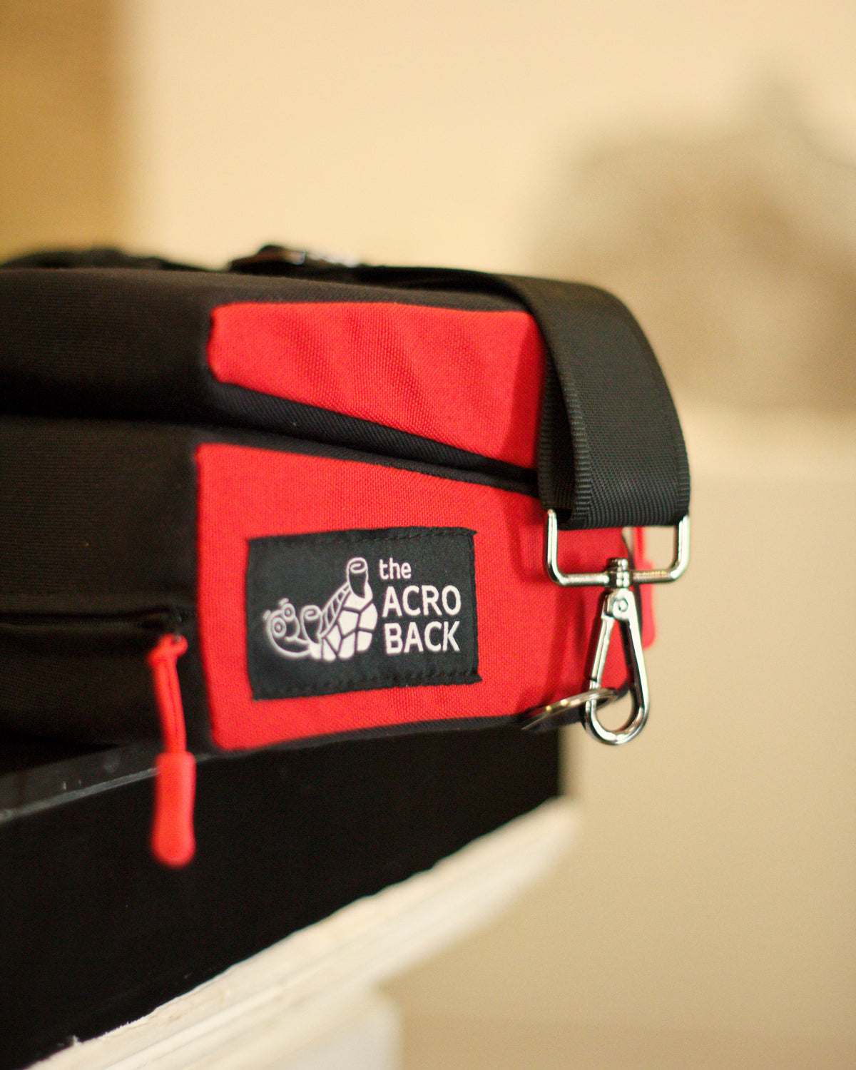 Red AcroBack Go folded closed, showing the carry strap attachment and logo