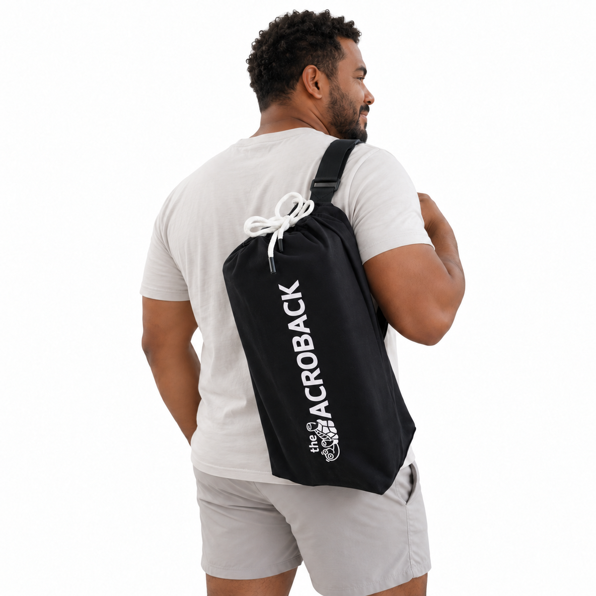 Rear three-quarter view of a man carrying the black AcroBack Travel Bag over one shoulder.