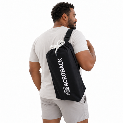 Rear three-quarter view of a man carrying the black AcroBack Travel Bag over one shoulder.